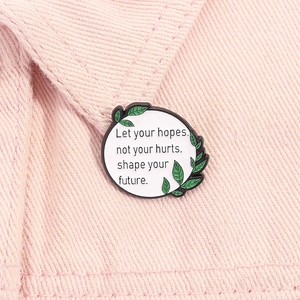 Détail d'un pin's émaillé inspirant avec feuilles vertes sur veste en jean rose