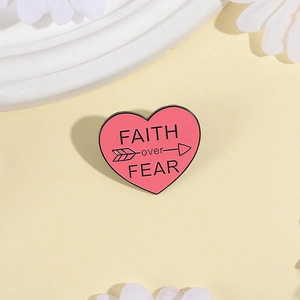 Minimalist heart enamel pin featuring Faith Over Fear design on soft yellow background