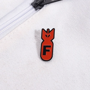 Macro shot of a red missile enamel pin with a black letter F on white canvas fabric