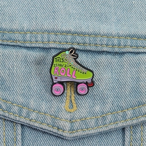 Close-up of a green roller skate enamel pin with text attached to a blue denim jacket pocket