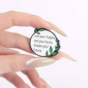 Macro detail of round enamel pin with motivational text held against a purple background