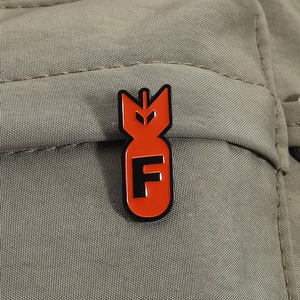 Macro shot of a red enamel F letter bomb pin on khaki textured nylon fabric material