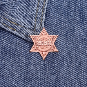 Rose gold sheriff star metal badge accessory pinned on denim jacket pocket