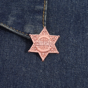 Macro shot of rose gold sheriff star badge with intricate engraving on denim fabric