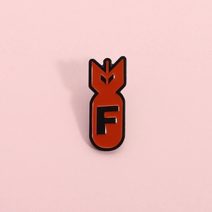 Macro view of red enamel bomb shaped pin with black letter F detail for casual wear