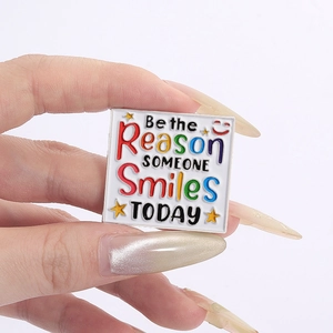 Gros plan d'une broche carrée en émail avec citation positive Be the Reason Someone