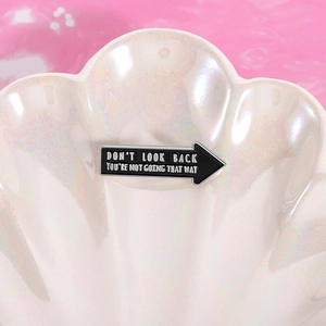 Macro shot of an arrow brooch with the quote DON'T LOOK BACK on a white shell