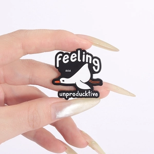 Macro detail of enamel goose brooch with Feeling ZZZ Unproducktive pun text on black base
