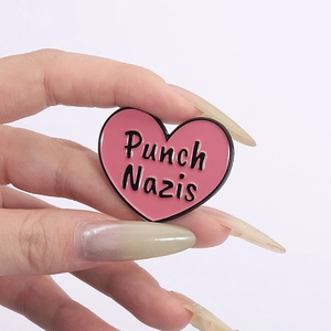 Pink heart-shaped enamel pin featuring Punch Nazis typography for backpacks or lapels