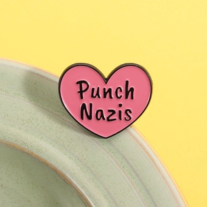 Pink heart enamel pin badge with Punch Nazis text over a bright yellow background