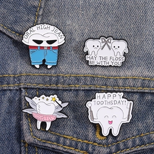 Lot de quatre pin's en émail en forme de dent sur un fond de tissu en denim bleu