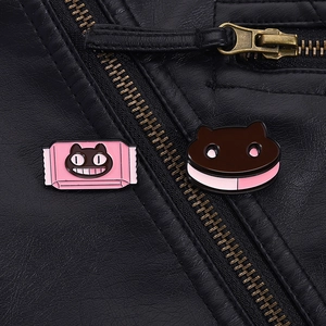 Detail of cute black cat enamel pins on leather jacket showing candy and cookie styles