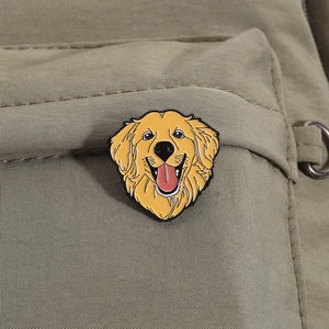 Cute golden retriever enamel pin accessory displayed on a green canvas backpack