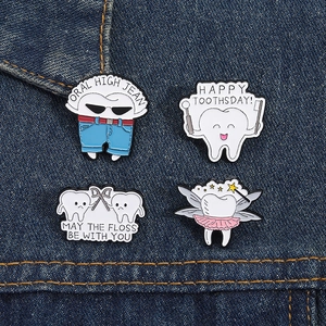 Lot de quatre pin's en émail en forme de dents sur denim, avec slogans dentaires drôles
