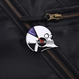 Close-up of a rotating skull gauge enamel pin on a black leather jacket collar