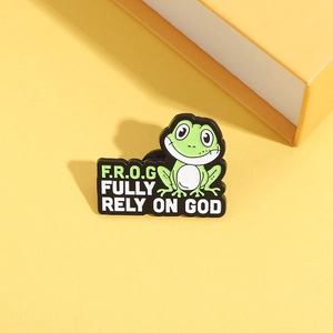 Detail van groene kikker emaille speld met de tekst Fully Rely On God op achtergrond