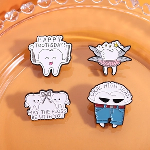 Set de pin's en émail à motif dent avec slogans amusants disposés sur une assiette en verre orange