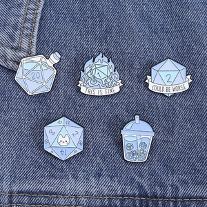 Set of five light blue enamel pins with d20 dice designs and slogans on denim background