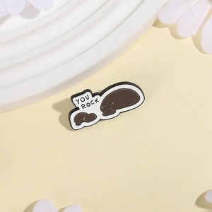 Creative stone shaped enamel pin with You Rock text on soft beige aesthetic background
