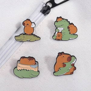 Detail view of four cute cartoon capybara and crocodile enamel pins on white canvas fabric