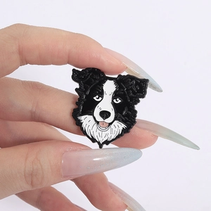 Detailed close-up of a black and white Border Collie enamel brooch held in hand