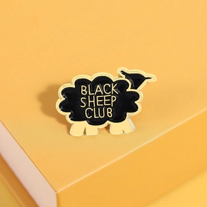 Détail du badge en émail de mouton noir avec lettrage jaune sur fond de boîte de luxe