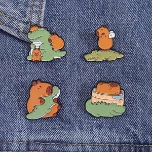 Detailed view of four cute enamel capybara and crocodile pins on blue denim fabric