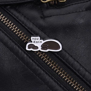 Close-up of You Rock manatee enamel pin on a black leather jacket with metallic zipper