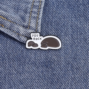Detailed view of the 'YOU ROCK' cartoon sea lion enamel pins on a blue denim jacket