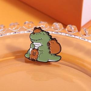 Detailed macro of a cute enamel pin featuring a green crocodile and capybaras on an orange base