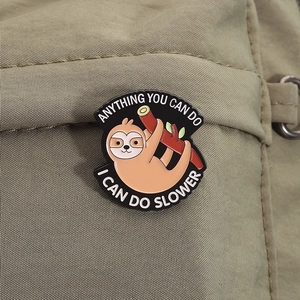Detail of sloth enamel pin with humor text on olive green canvas backpack bag