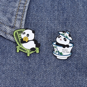 Detail of panda enamel pins with bamboo chair and tea cup designs on denim fabric