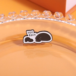 Macro shot of grey stone-shaped enamel pins featuring creative 'YOU ROCK' text detail