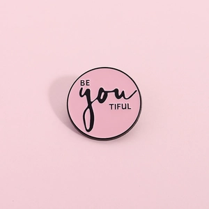 Détail de la broche en émail rose Be You Tiful avec contours en métal noir