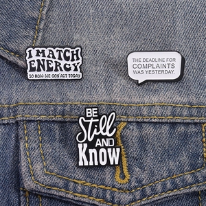 Three enamel quote pins including I Match Energy attached to a blue denim jacket pocket
