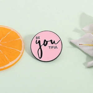 Pin's rond en émail rose avec texte BE YOU TIFUL et design musical géométrique créatif
