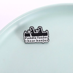 Enamel brooch with canoe silhouette and Paddle Faster I Hear Banjos slogan