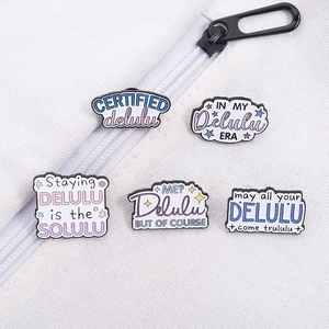 Lot de cinq épingles en émail Delulu colorées présentées sur un sac en toile blanc