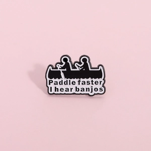 Close-up of enamel pin featuring a boat silhouette and Paddle faster text on pink background