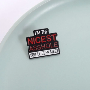 Schwarze Emaille-Anstecknadel mit rot-weißem Schriftzug 'I'M THE NICEST ASSHOLE'