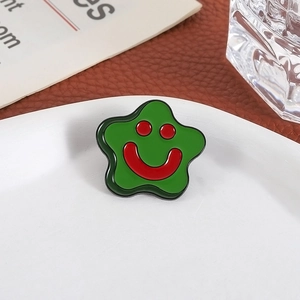 Creative green star-shaped brooch badge with red smiley face on white ceramic plate