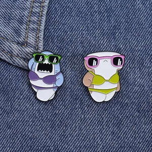Close-up of cute cartoon shark enamel pins in bikinis on denim fabric background