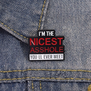 Detail der Emaille-Anstecknadel auf Denim mit dem Spruch I'M THE NICEST ASSHOLE YOU LL EVER MEET