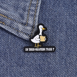 Vue macro du pin's canard blanc en émail avec texte humoristique sur tissu denim bleu