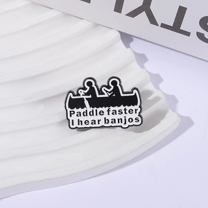 Black and white metal enamel pin featuring silhouettes of people rowing a boat with humor text