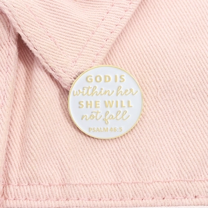 Gros plan d'une broche en émail blanc avec citation biblique sur tissu en denim rose