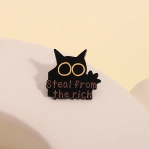 Detailed view of punk black cat enamel pin with yellow eyes and Steal from the rich slogan