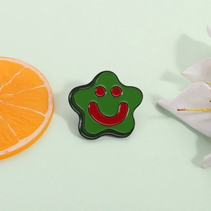 Cute green star enamel brooch pin with a happy smiling face on light green floral background