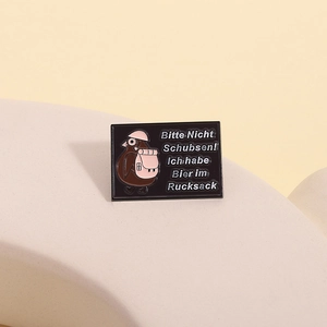 Vue détaillée du pin's émaillé avec motif de pigeon et texte bière allemand sur métal noir