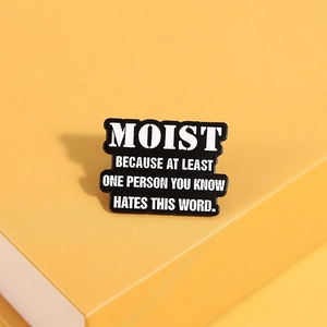 Detail showing enamel pin with funny text Moist Because At Least One Person Hates This Word